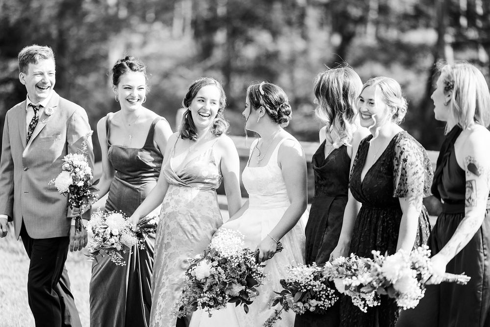 Black and white photo of wedding party holding bouquets in outdoor setting.