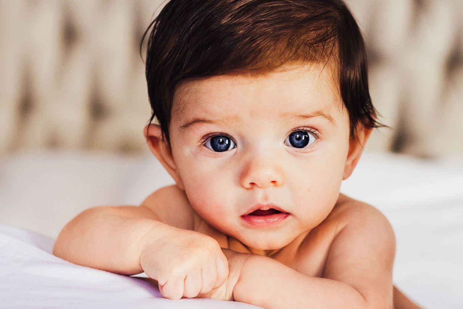 In home infant lifestyle photo session of baby girl with large eyes and dark hair portrait