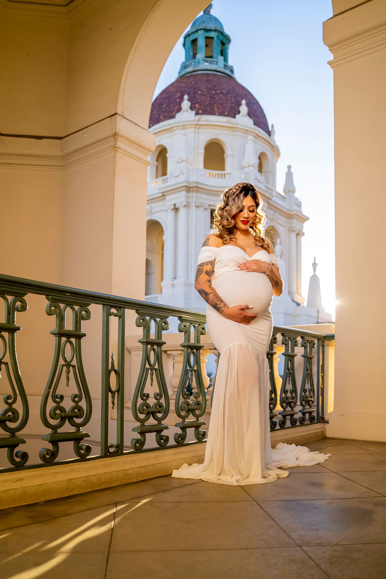 A maternity portrait with a domed building in the background showing an elegant white dress.