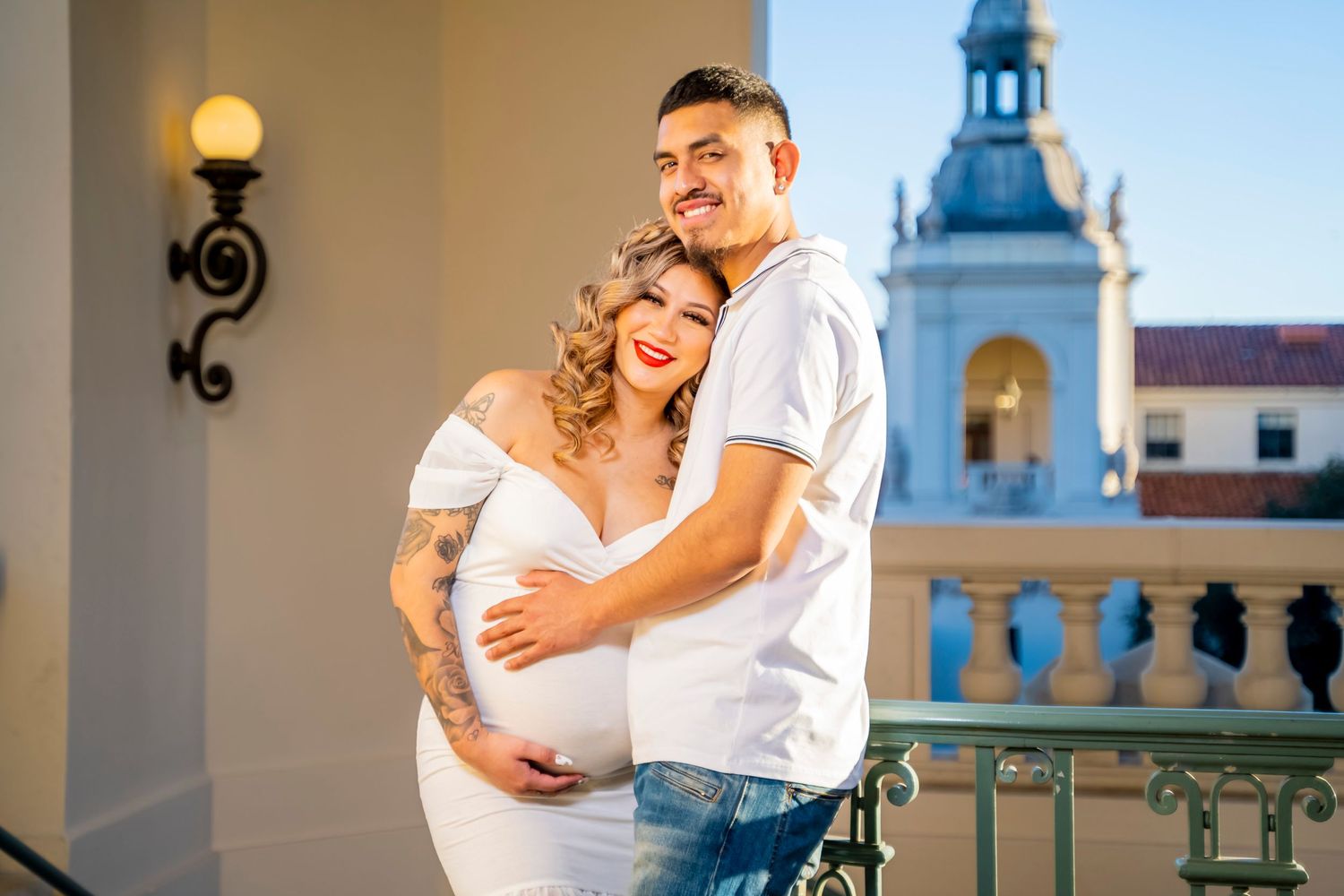 A maternity photo featuring a couple posing against historic architecture and a church spire.