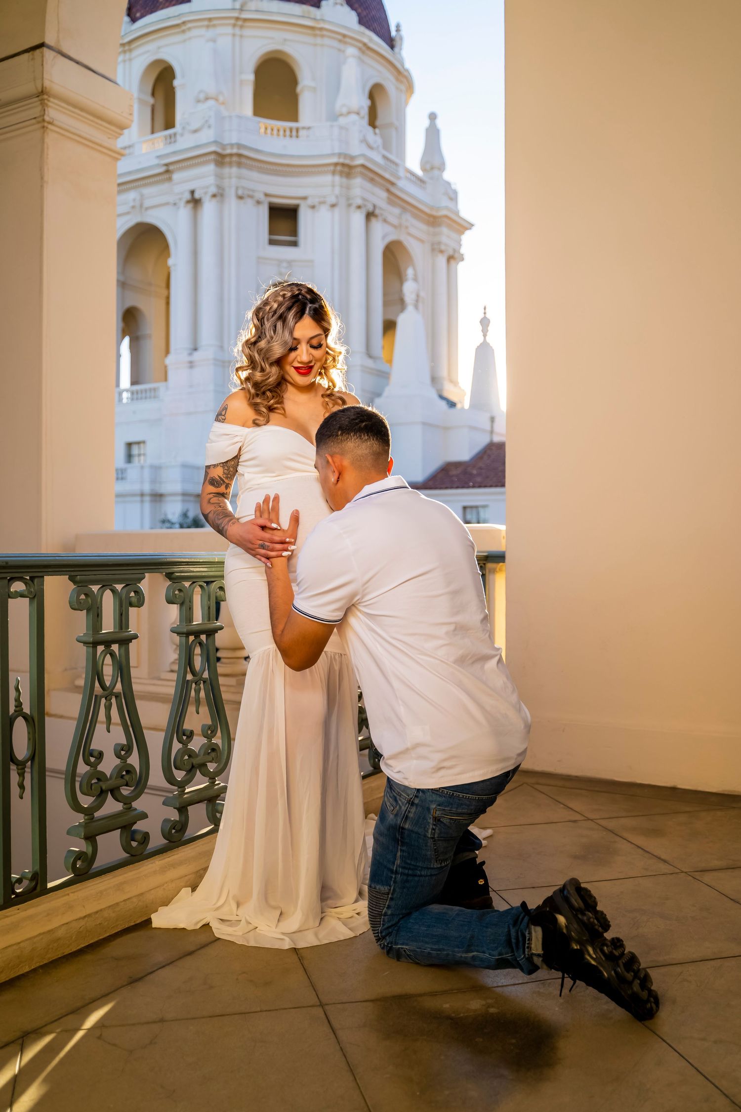A maternity photo showing an intimate moment on a balcony with classical architecture.