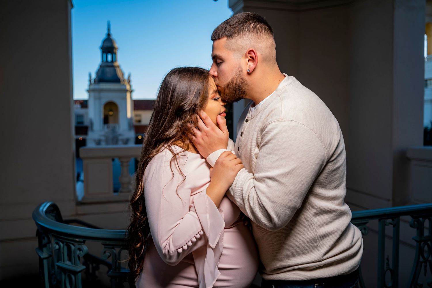 A romantic maternity portrait captured in an architectural setting with arched windows.