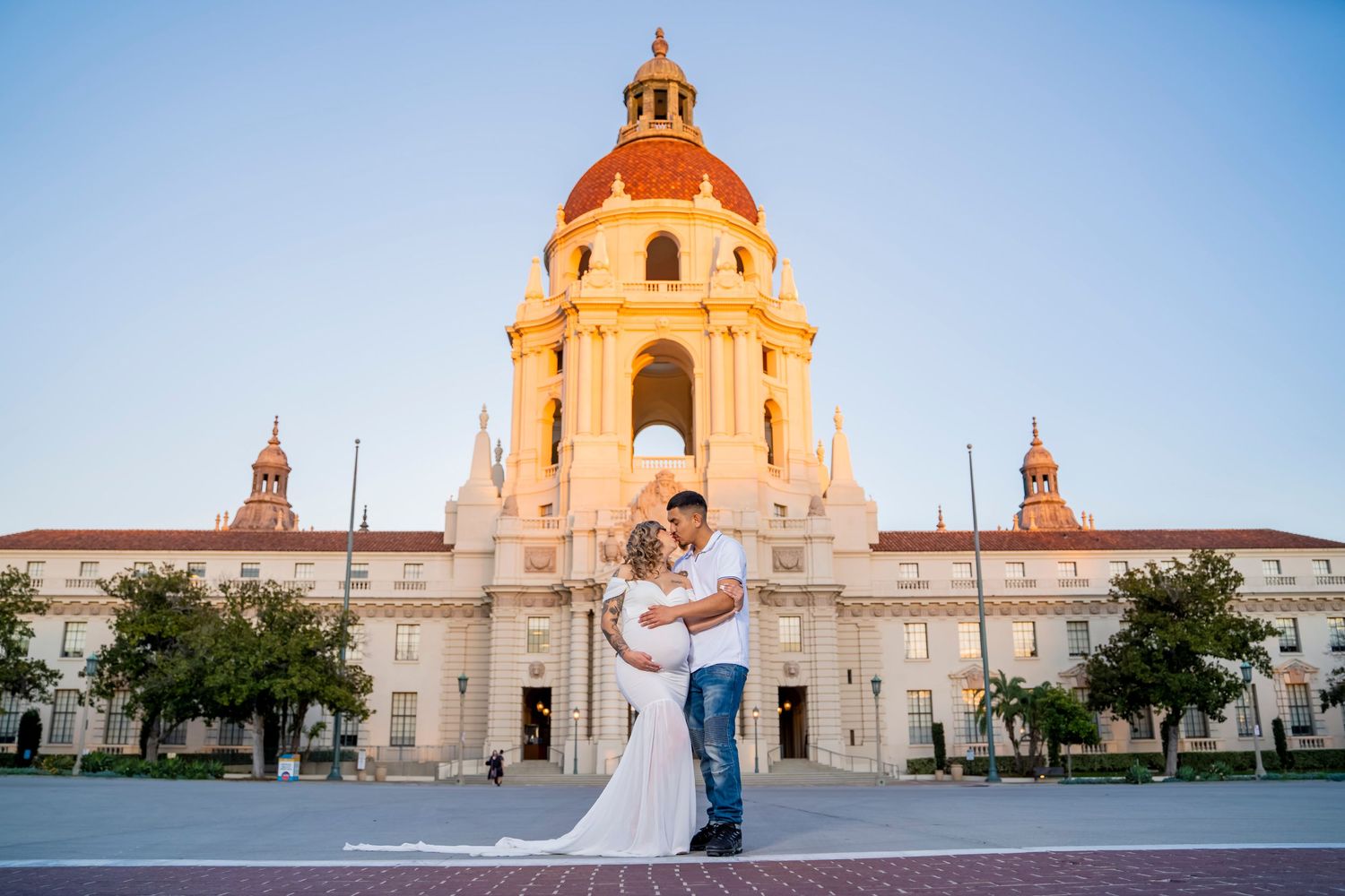 A wedding couple poses in front of Pasadena City Hall's iconic dome during golden hour.