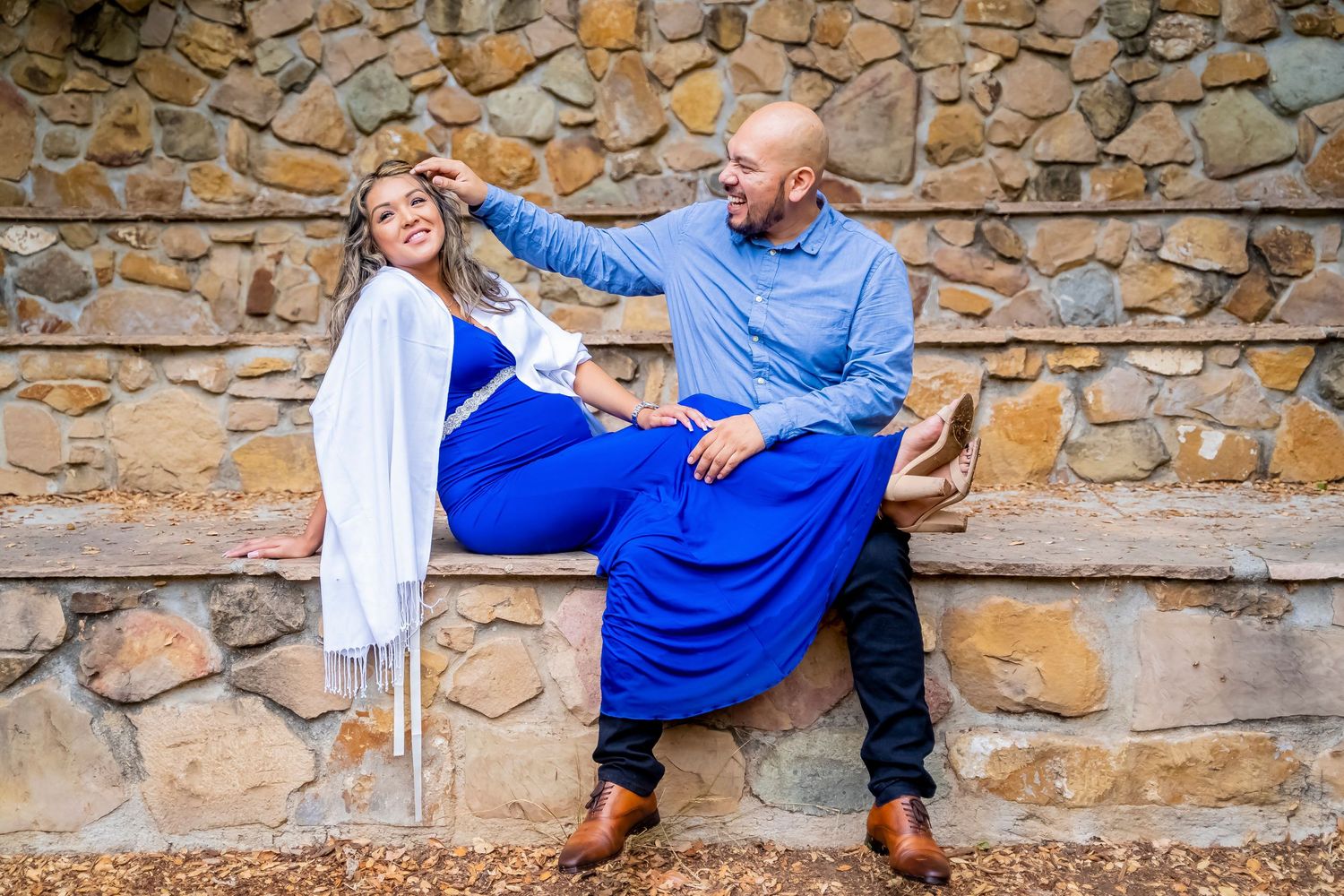 Couple relaxing on stone steps during maternity photoshoot.