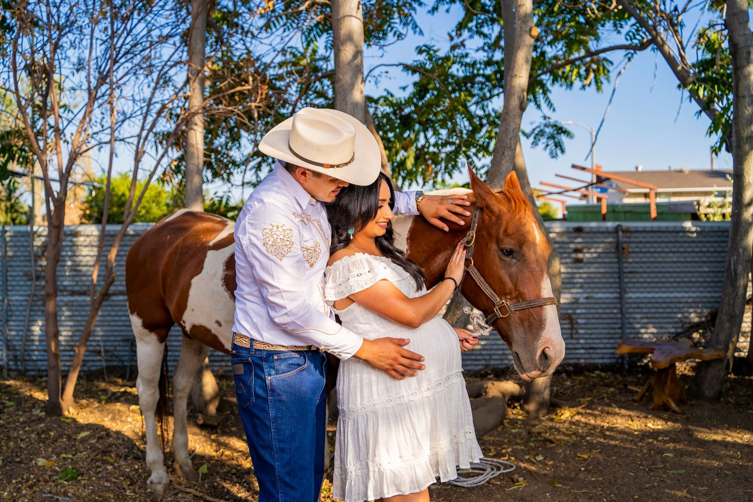 Couple sharing tender moment with paint horse in rustic ranch setting.