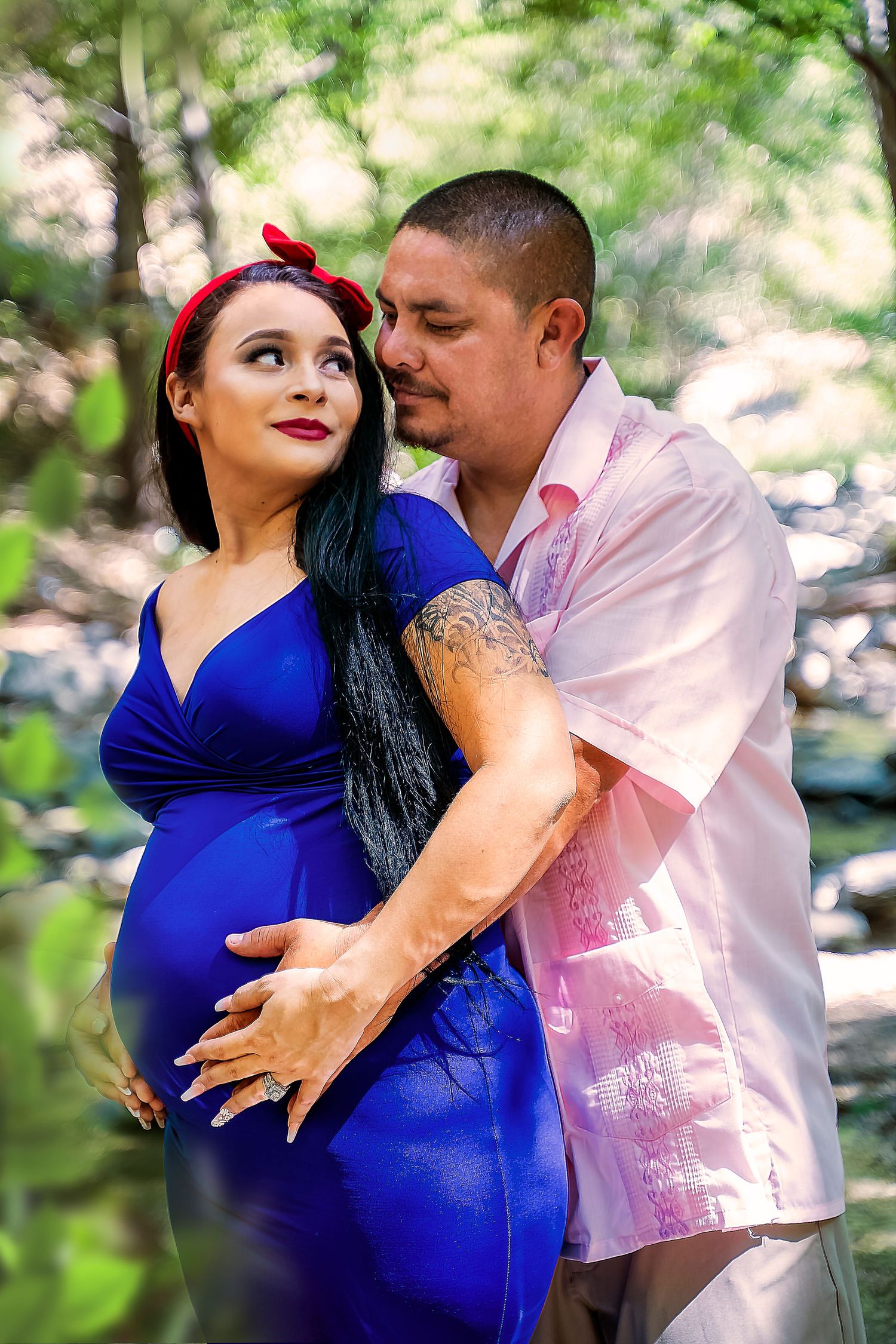 A loving couple embraces during maternity photoshoot wearing pink and blue outfits.
