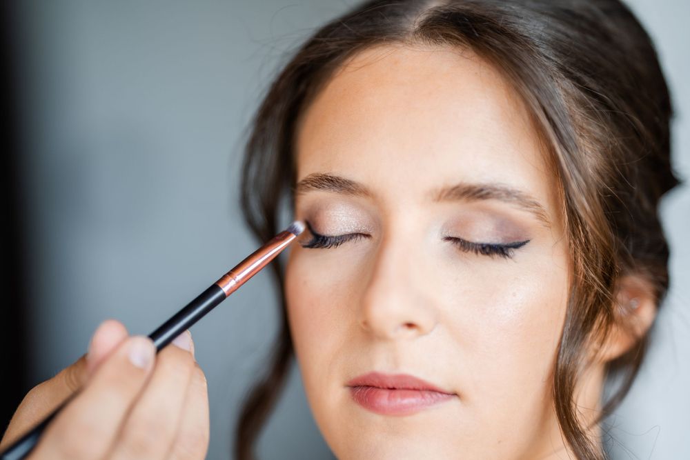Professional makeup artist applying eyeshadow with a brush for bridal look.