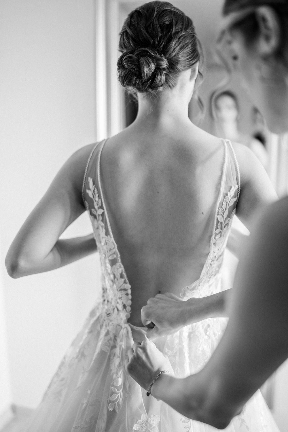 Back view of an elegant lace wedding dress being fastened.