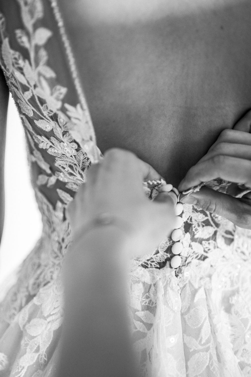 Black and white detail of intricate lace pattern on wedding dress.