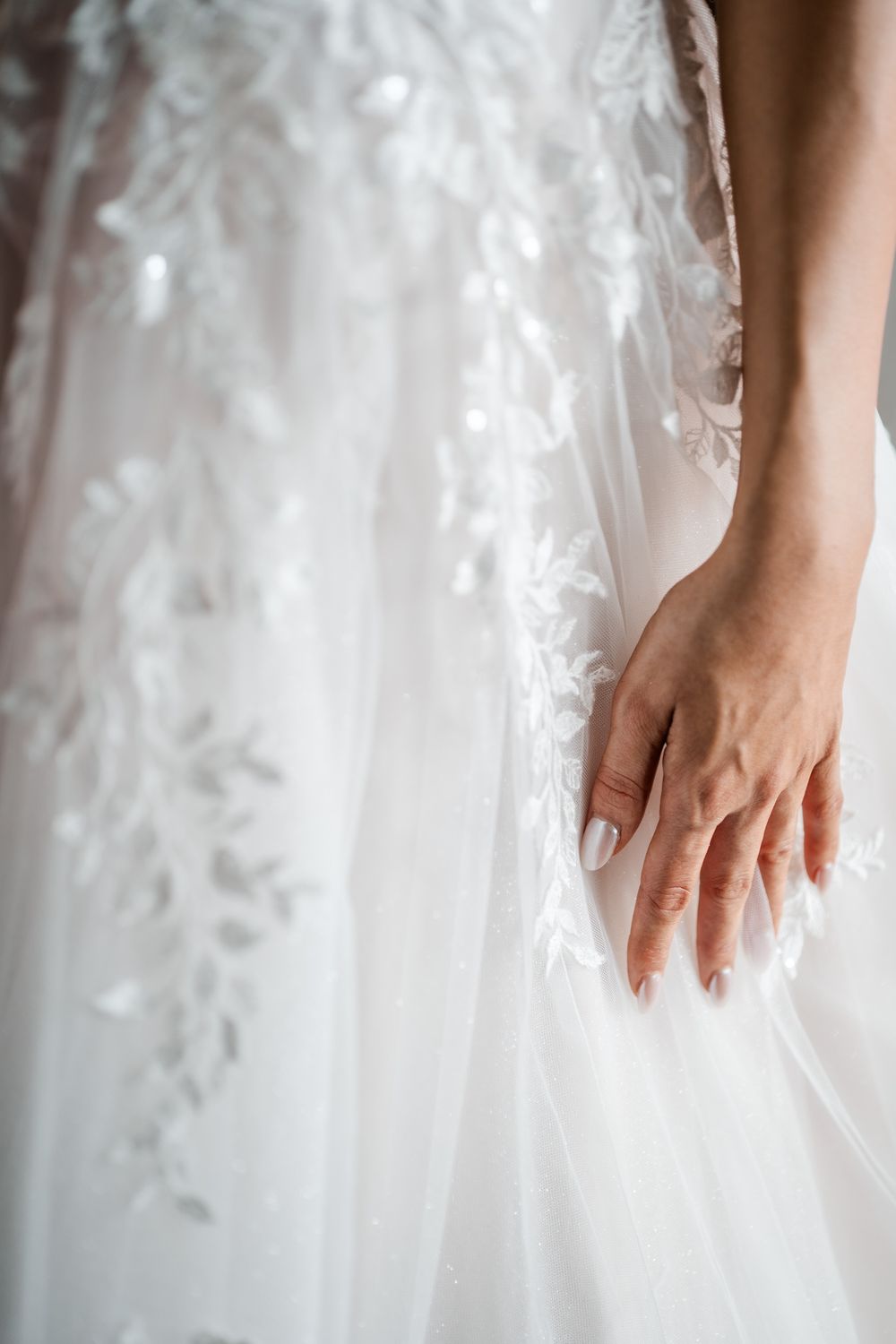 Close-up of delicate lace and tulle details on white wedding dress.