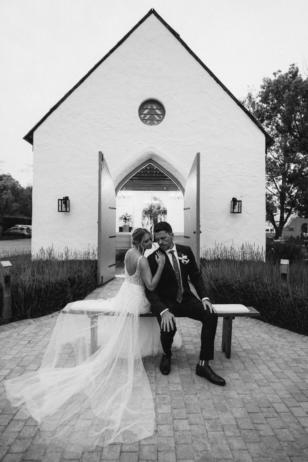 couple posing on a bench infront of the Erinvale chapel