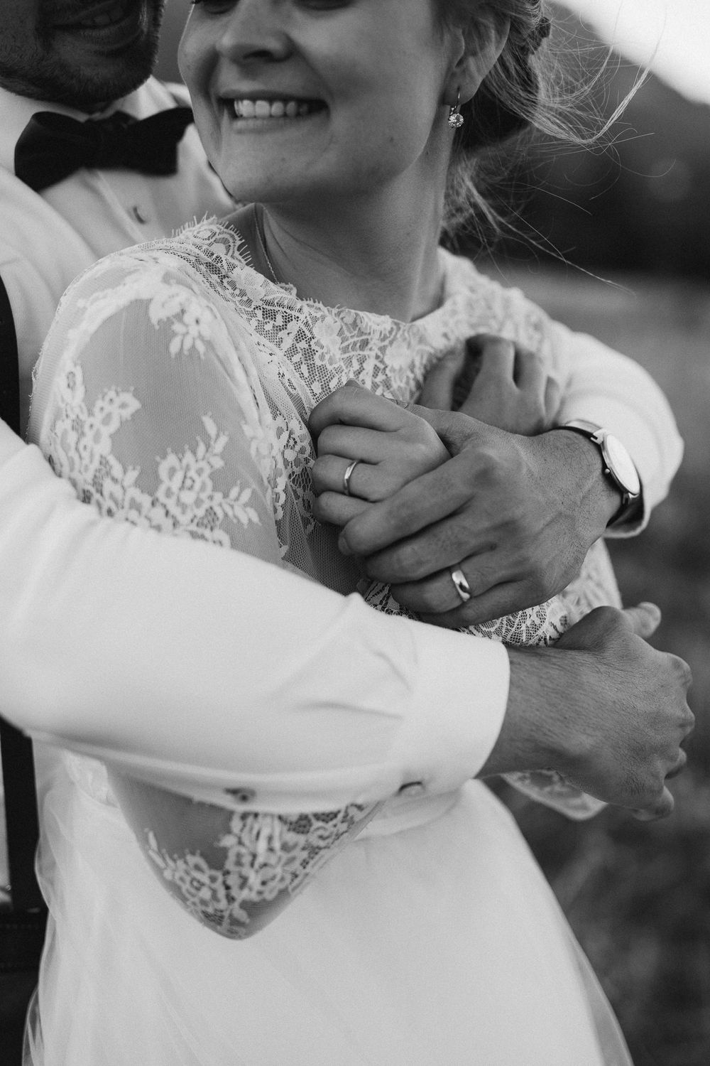 groom hugging his wife from behind in a b&w photo
