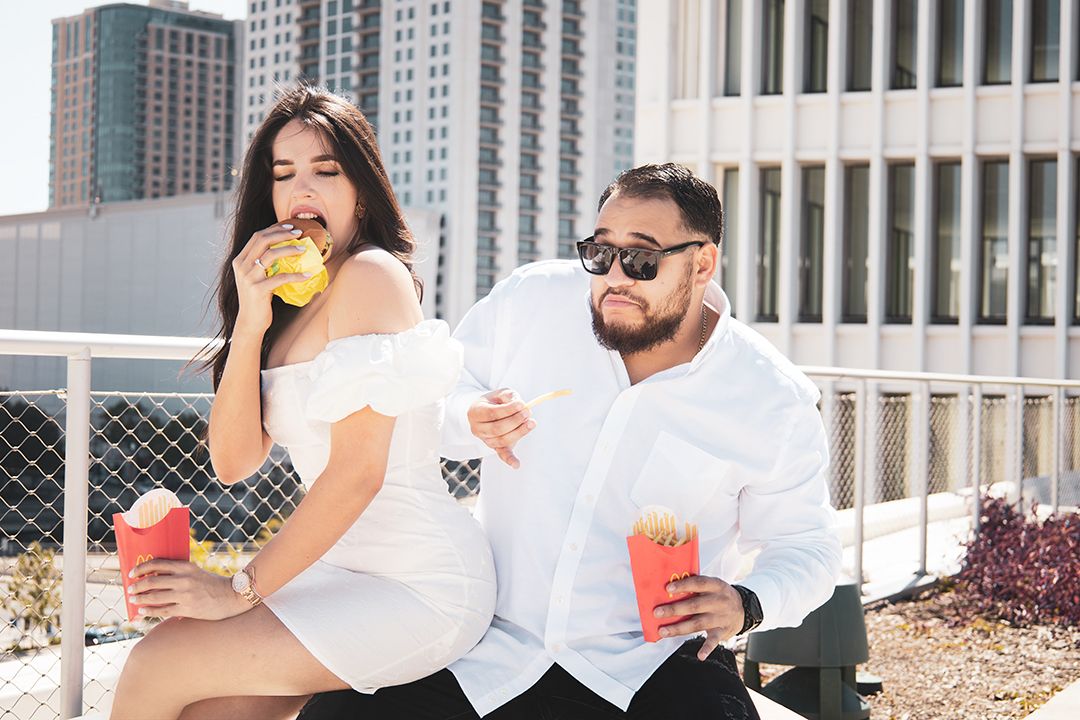 Two people enjoying fast food and drinks on an urban rooftop setting.
