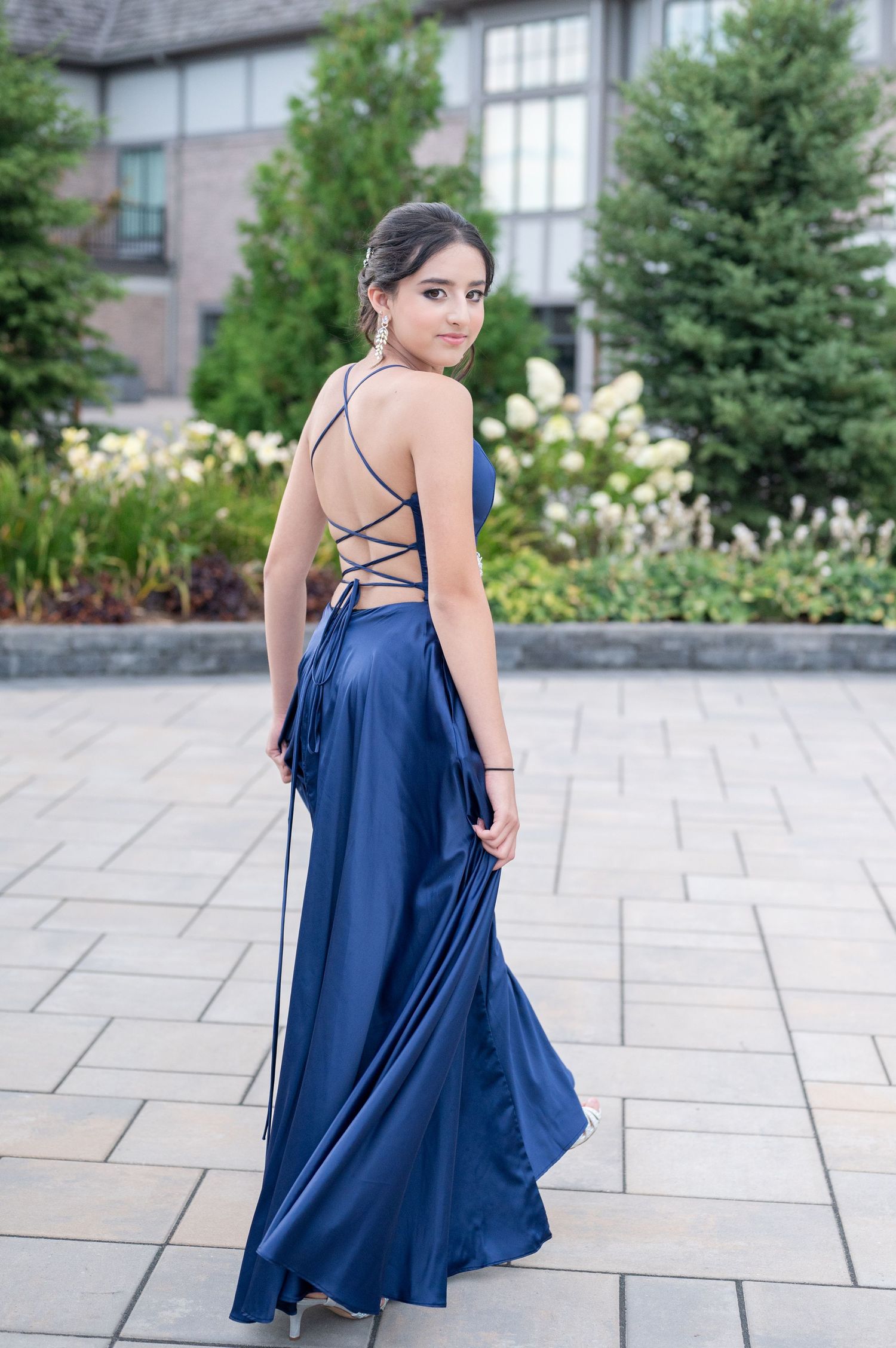 Back view of navy blue formal dress with criss-cross straps against stone building.