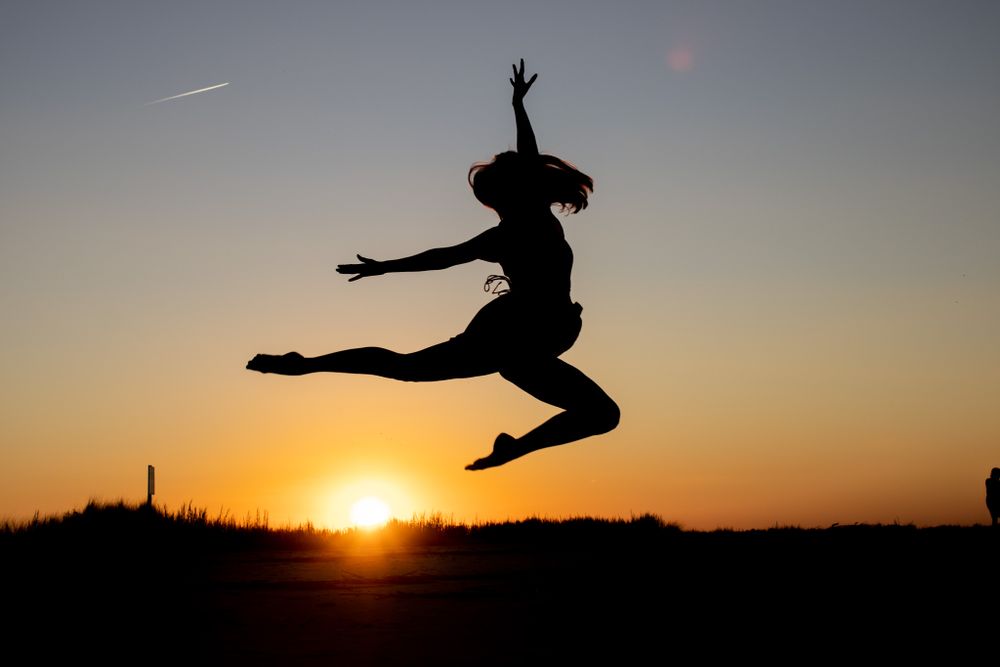 Silhouette of a woman leaping at sunset