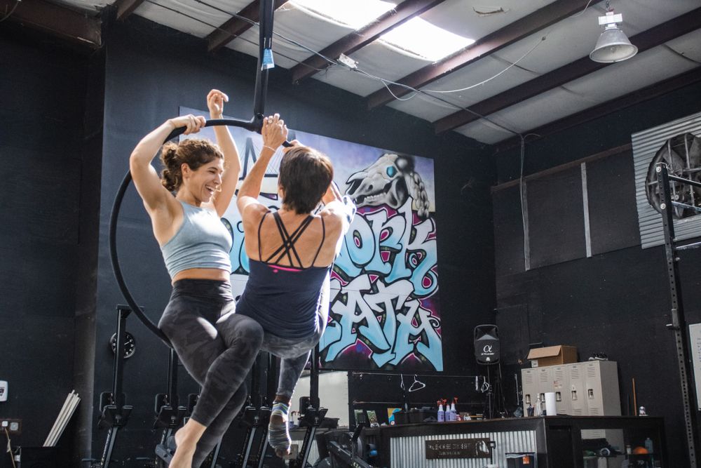 Two women seated on a Lyra hoop