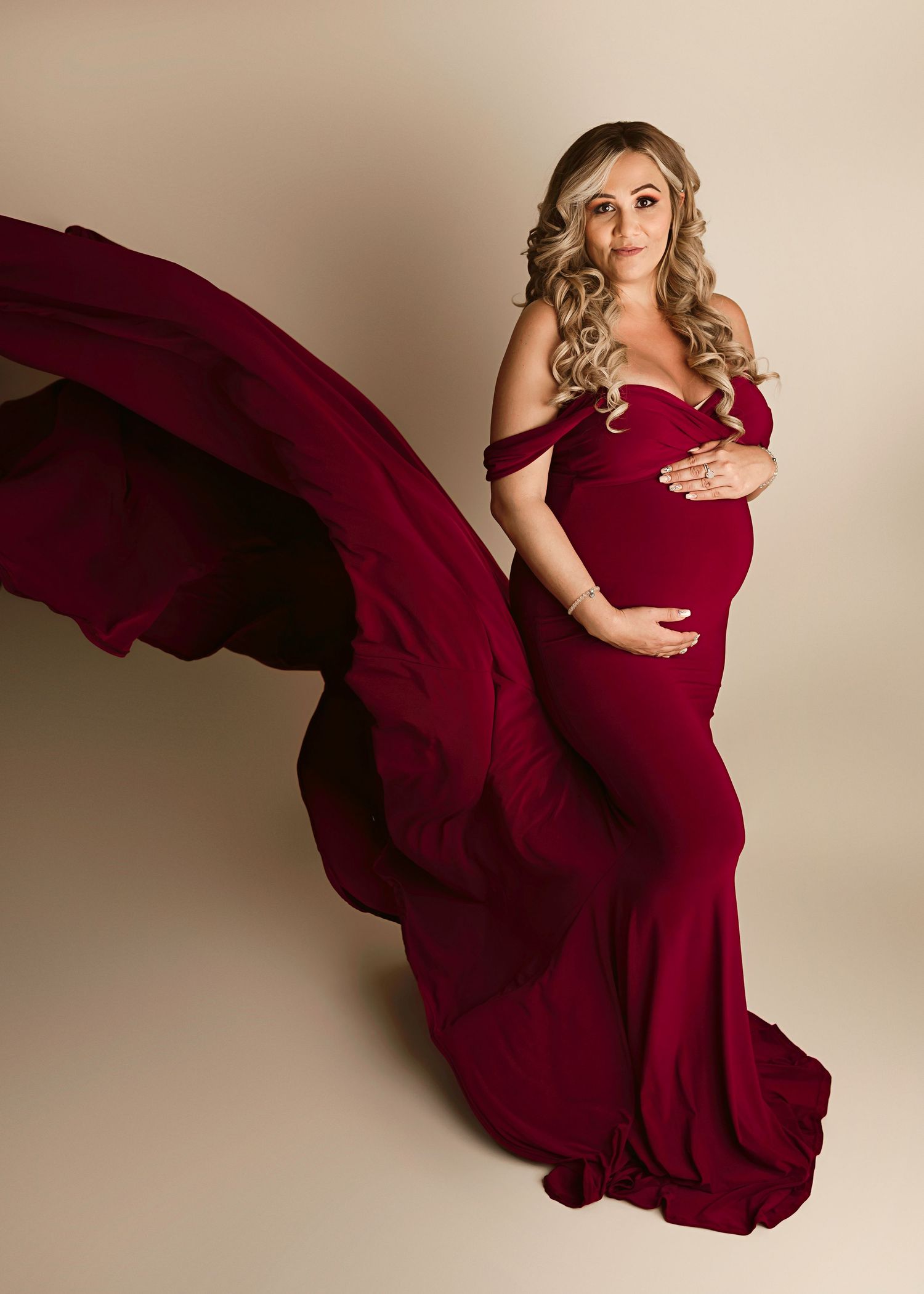 Maternity pictures Riverside, pregnant woman in wine red maternity gown looking at camera