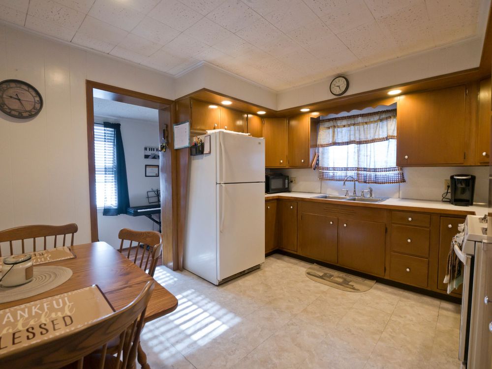 Retro kitchen with wooden cabinets, white appliances, and round dining table.