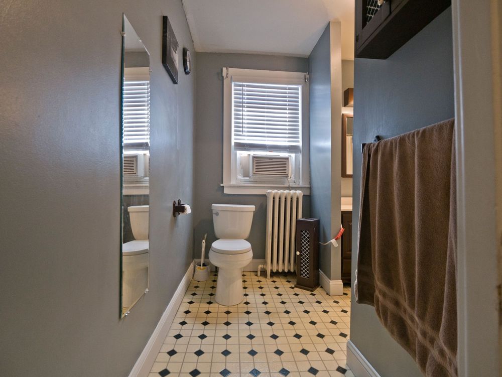 Modern bathroom with black and white tile flooring, wall-mounted radiator, and a neutral color scheme.