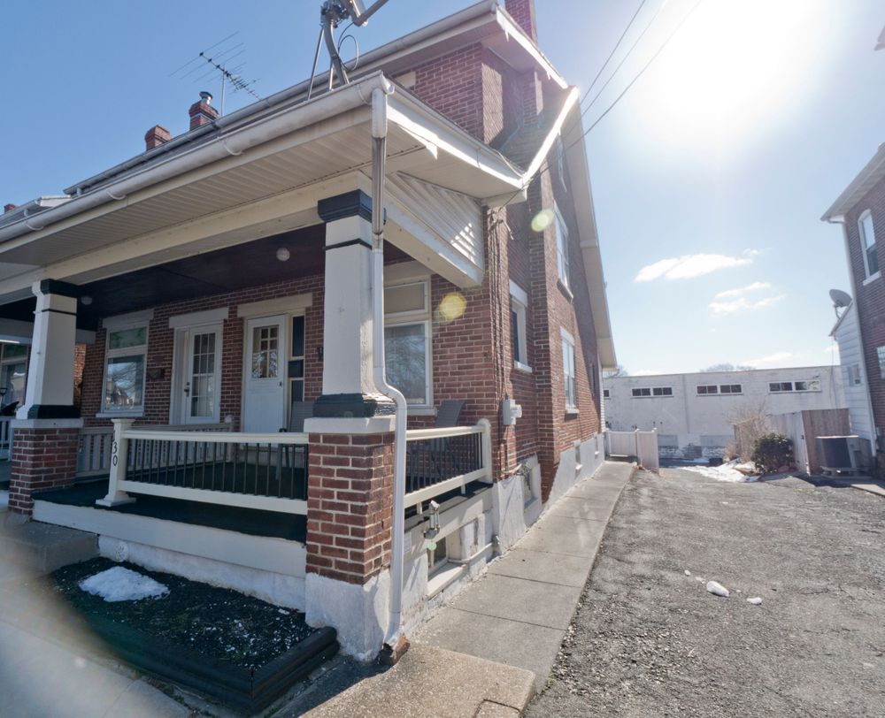 Brick rowhouse with covered front porch and white columns on a winter day.