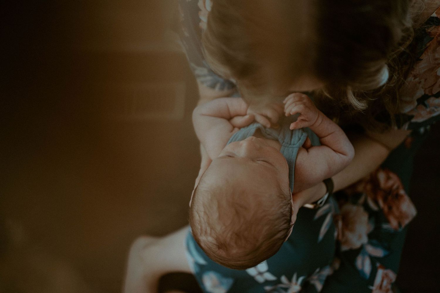 A tender moment captured of a baby being held with soft lighting.