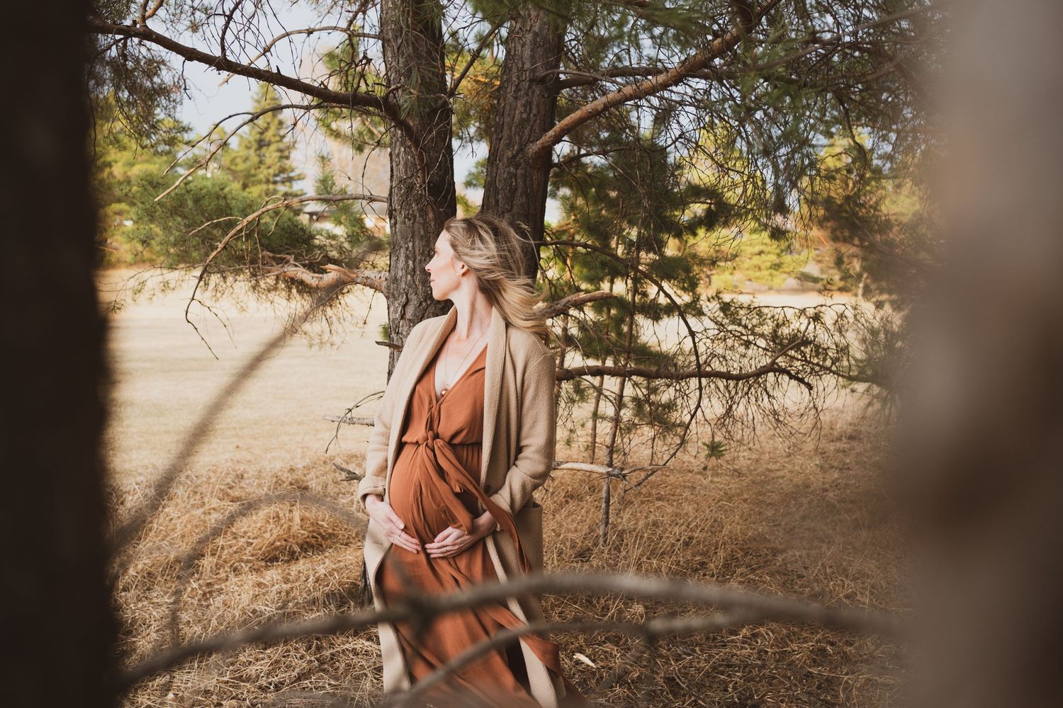 Dreamy maternity photo in natural setting with warm autumn colors and tree shadows.