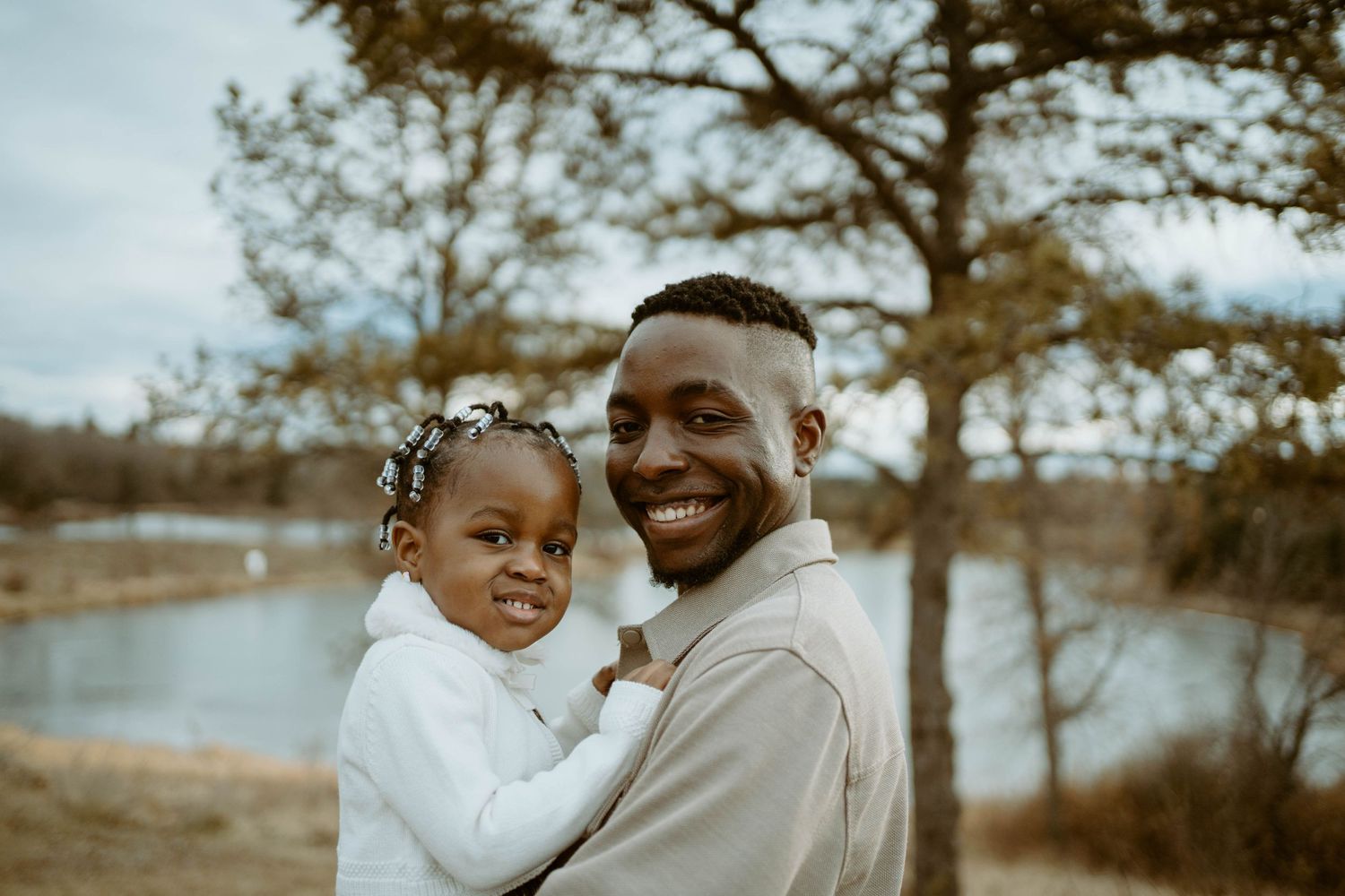 A tender outdoor portrait showing warmth and love between parent and child near a lake.