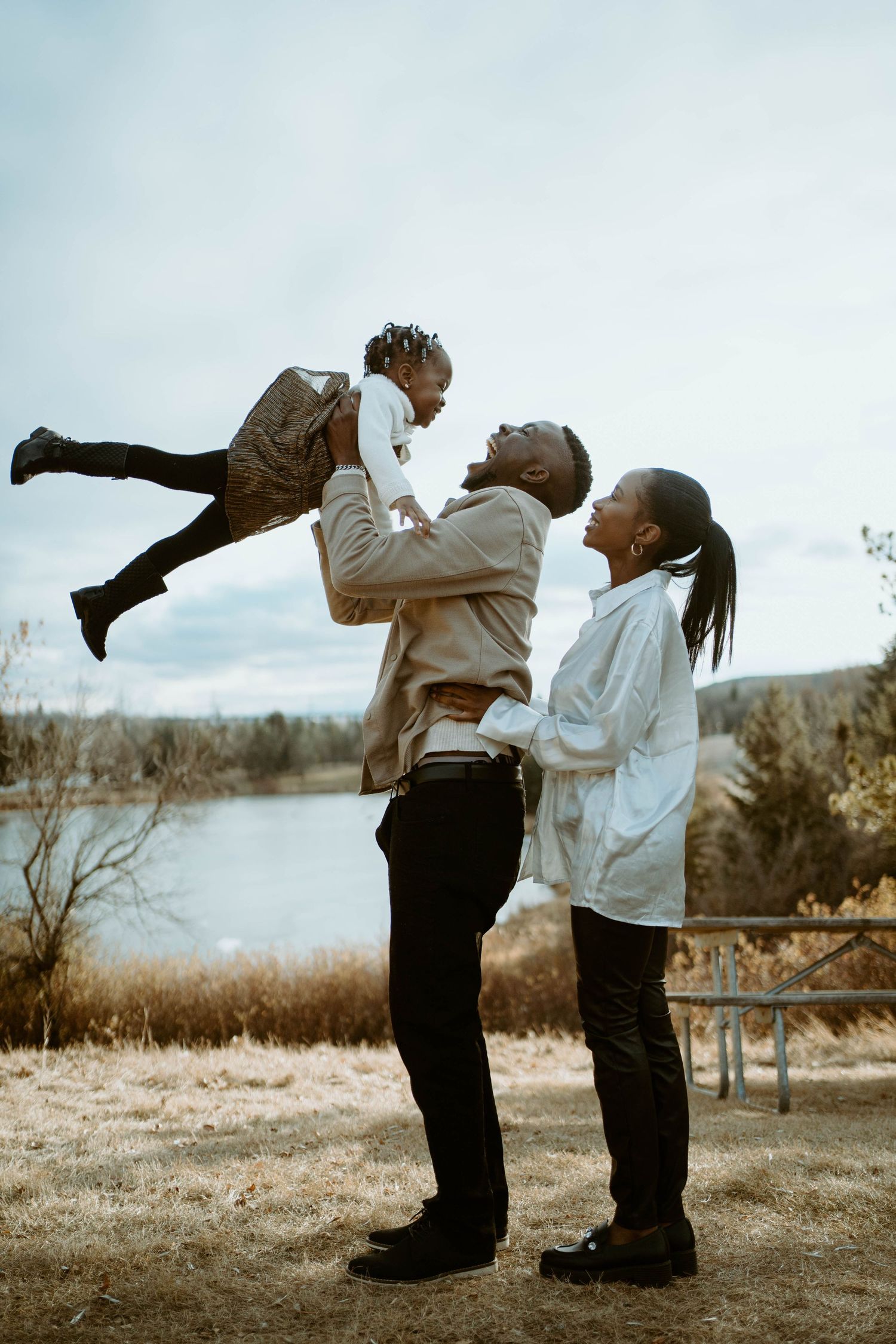 A joyful family moment captured outdoors as they play and lift their child in the air.
