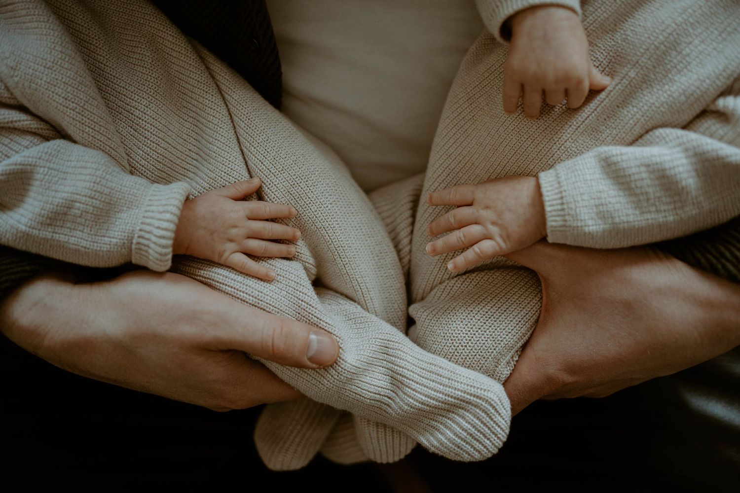 Intimate photo of hands holding knitted socks against cozy sweater fabric.