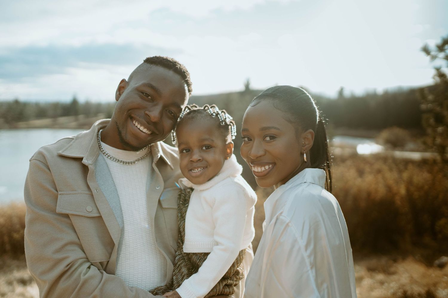 A happy family moment captured against a scenic lake backdrop on a bright day.