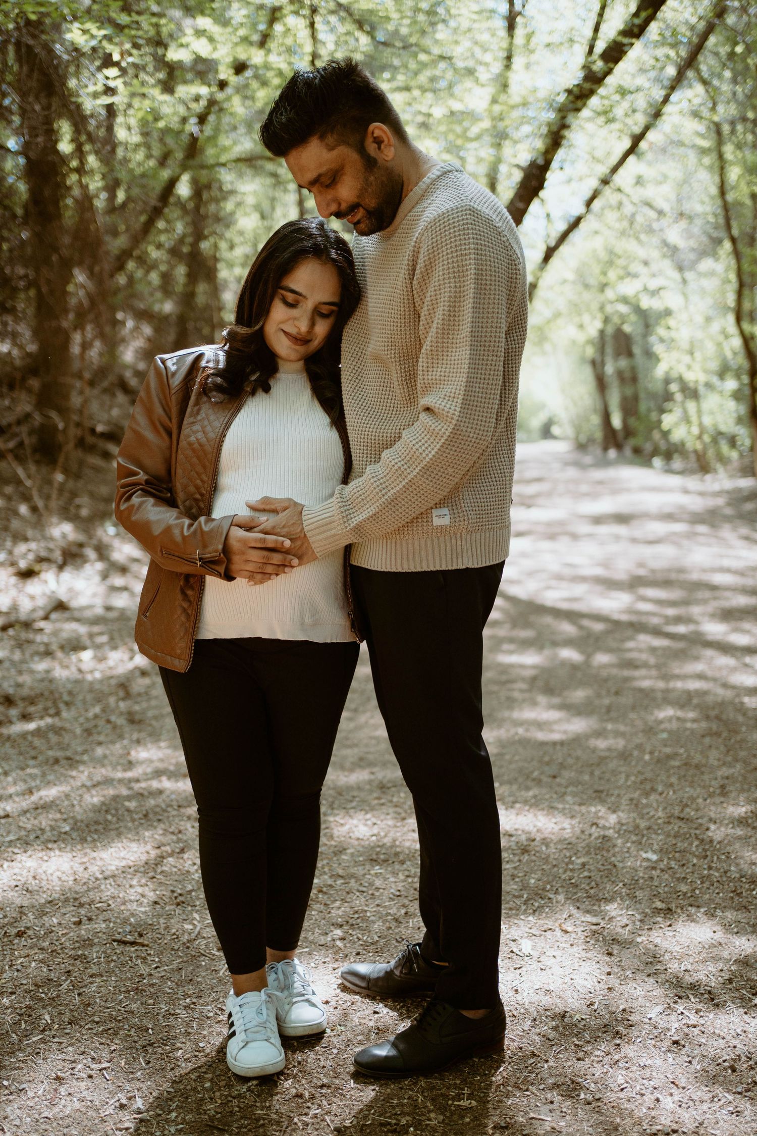 A cozy autumn forest scene with a couple in matching sweaters for a maternity session.