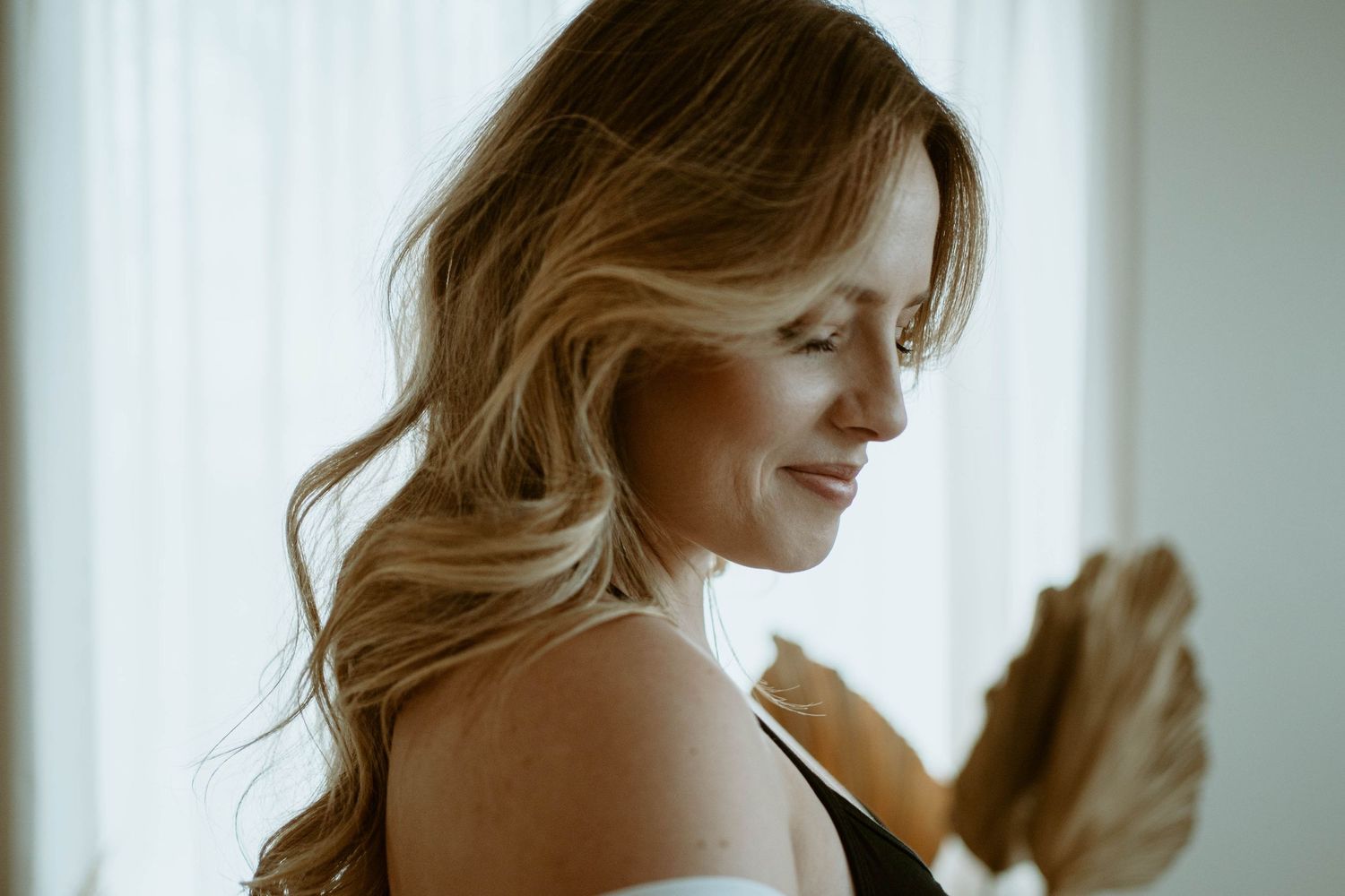 Soft profile portrait in natural window light with flowing blonde hair.