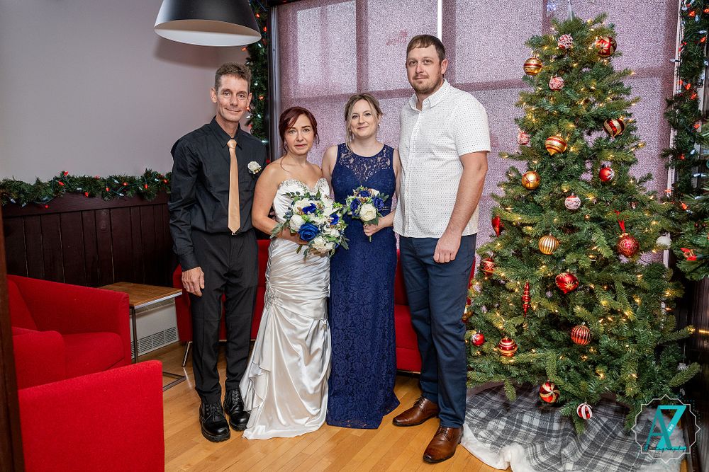 Formal group photo with Christmas tree, red couch and holiday decorations.