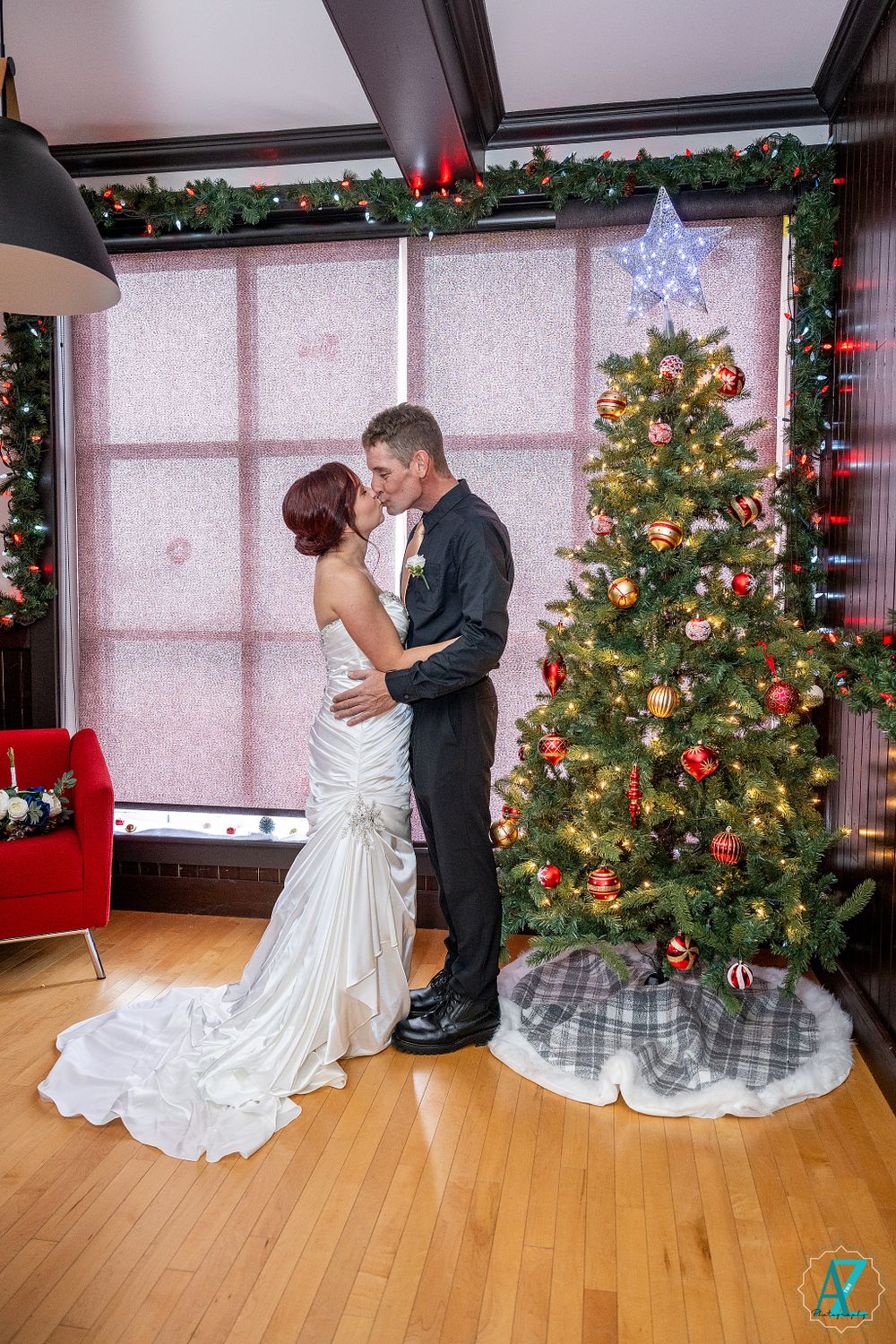 Elegant winter wedding scene with couple embracing near decorated Christmas tree.