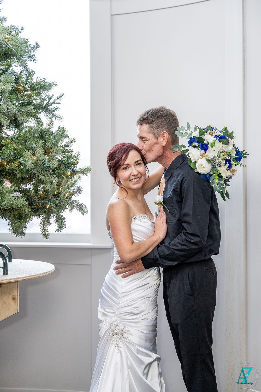 Romantic moment captured between couple in formal attire with blue and white bouquet.