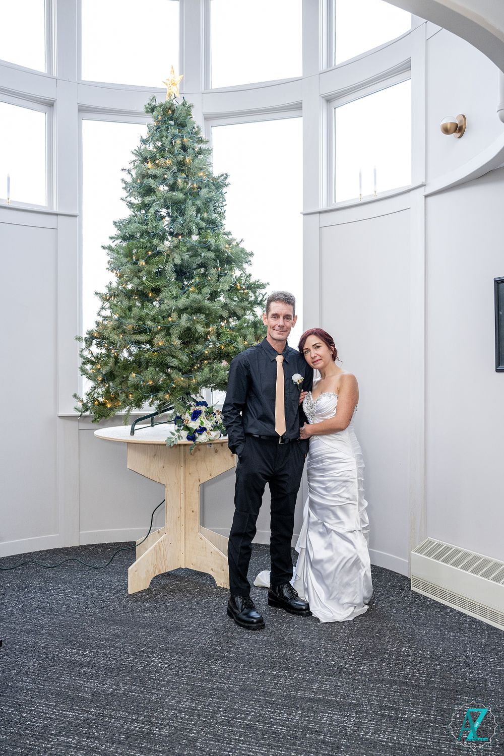 Formal wedding portrait with Christmas tree and wooden table decor.