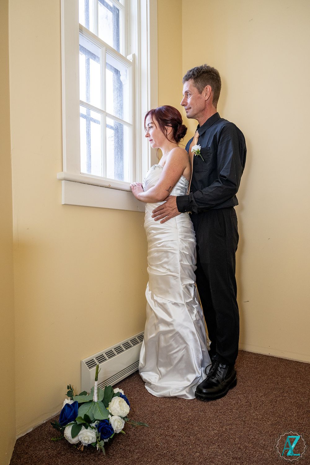 Romantic window portrait of couple in formal wedding attire.