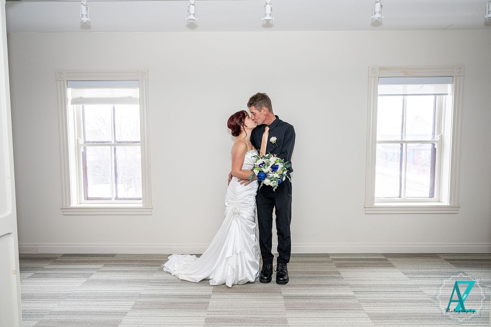Romantic couple embraces while sharing a tender moment in a minimalist white room.