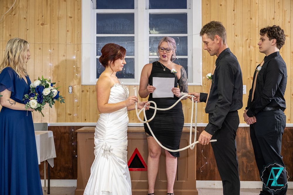 Wedding ceremony proceedings with attendants in formal attire against wood-paneled walls.