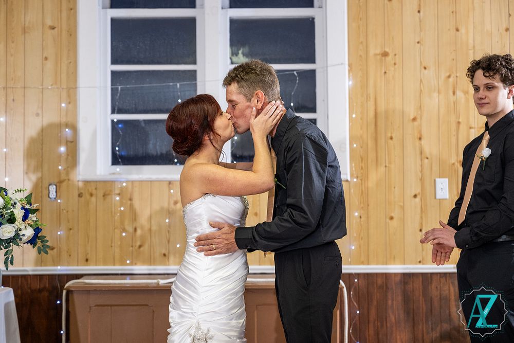 Romantic wedding ceremony moment in a wood-paneled venue with natural lighting from windows.