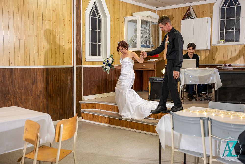 Celebratory dance moves in a wood-paneled reception hall with gothic windows and white table settings.