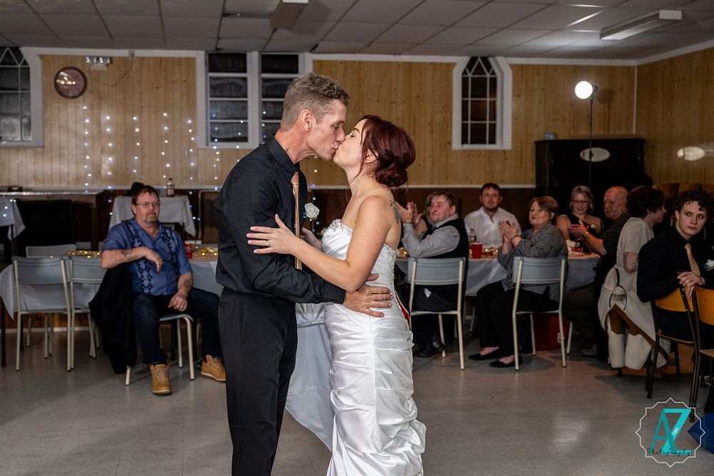 Romantic dance scene in a wood-paneled church hall with string lights and seated guests.