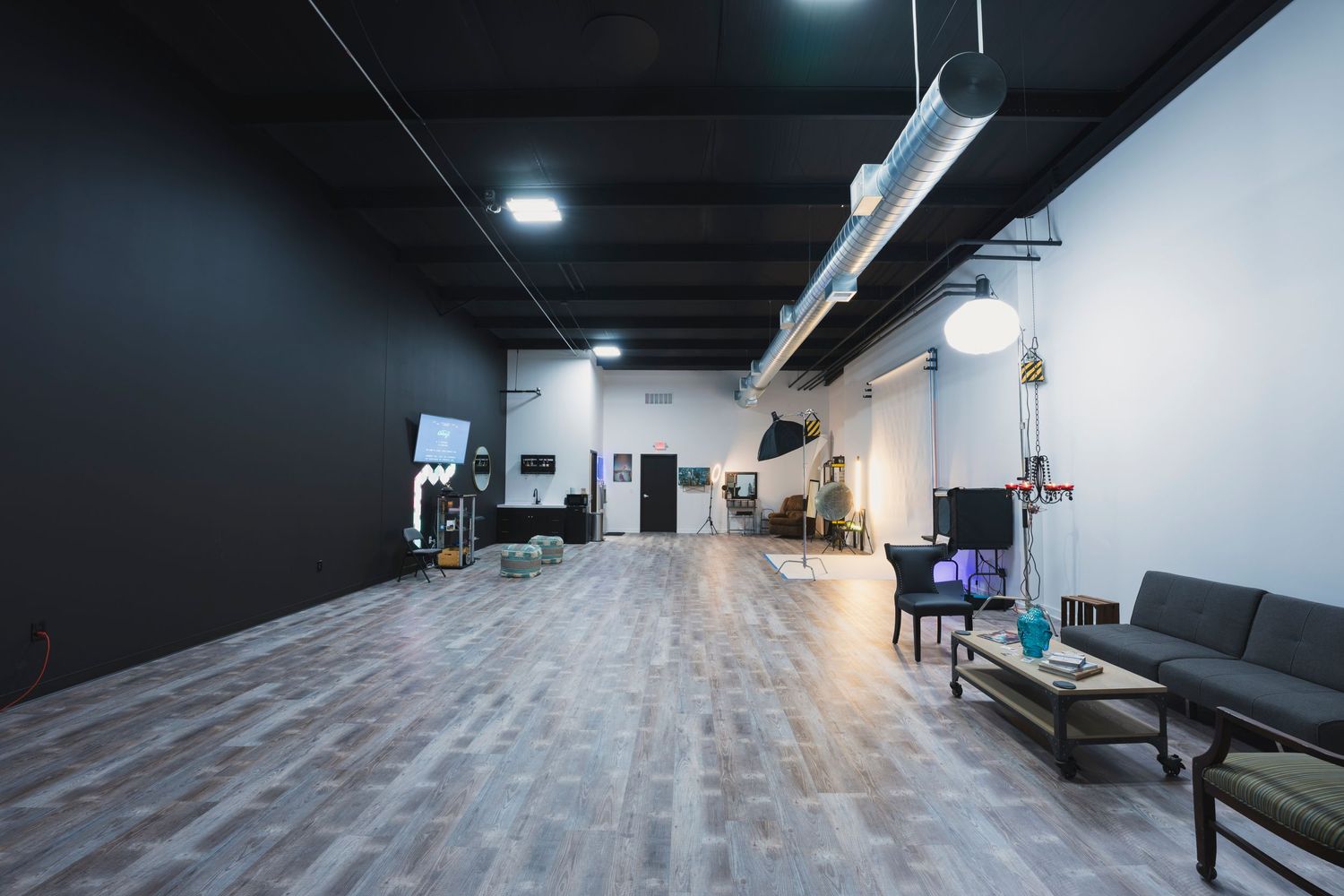 Spacious photography studio with dark ceiling, wood floors and minimalist industrial design.
