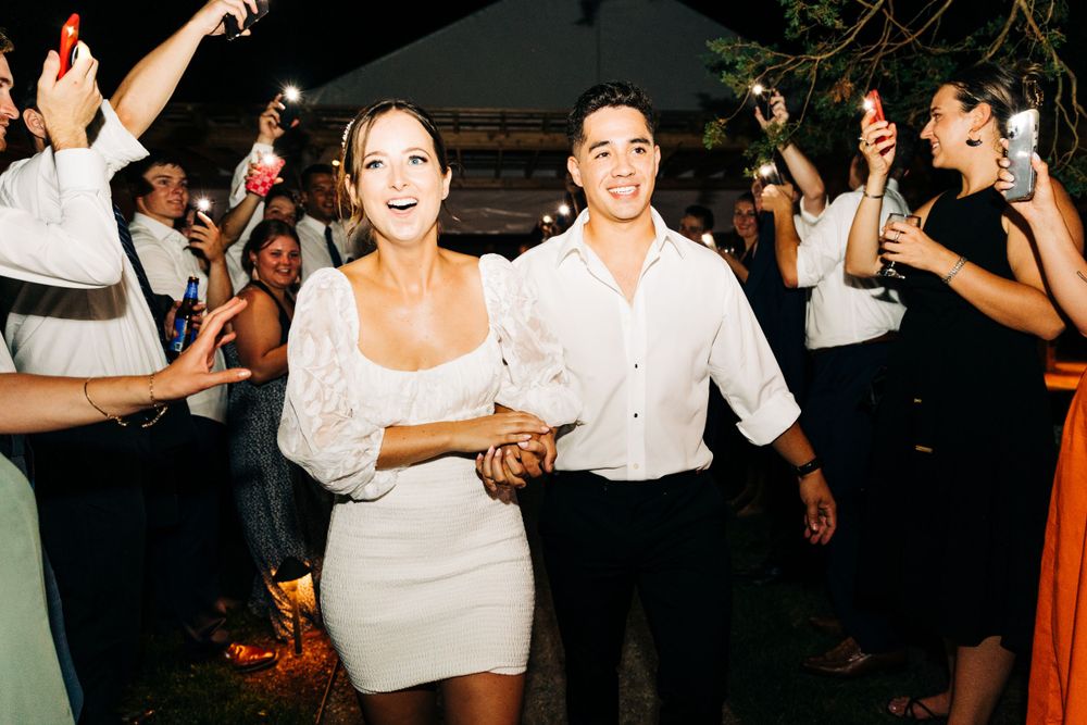 Couple dancing together at a nighttime wedding celebration surrounded by guests.