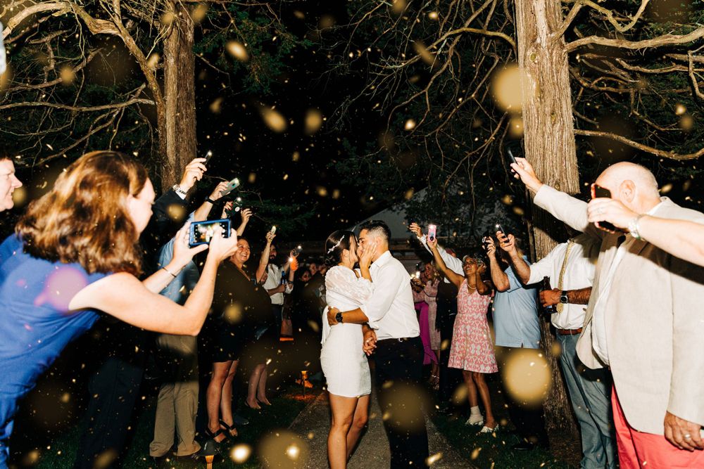 Wedding celebration at night with guests throwing sparklers in the air.