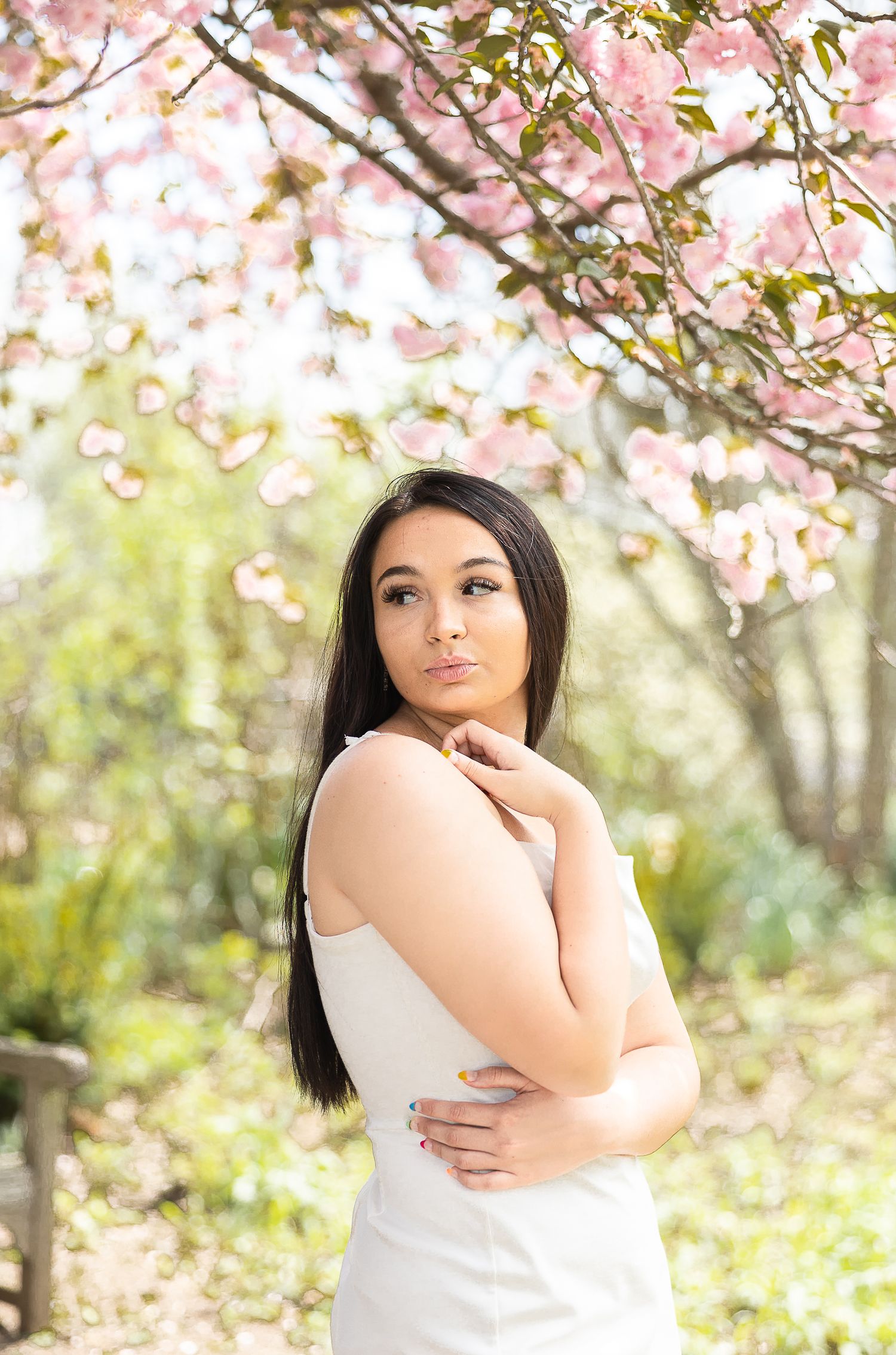 Spring portrait under cherry blossoms with soft bokeh background.