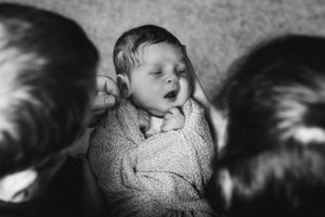 A black and white portrait of a yawning baby bundled in a cozy sweater.