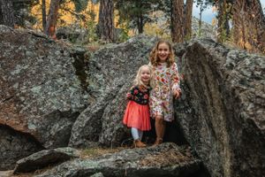 Candid portrait among large forest boulders with autumn trees in the background.