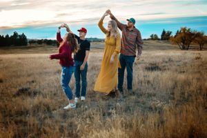 A family twirls in a golden prairie field.