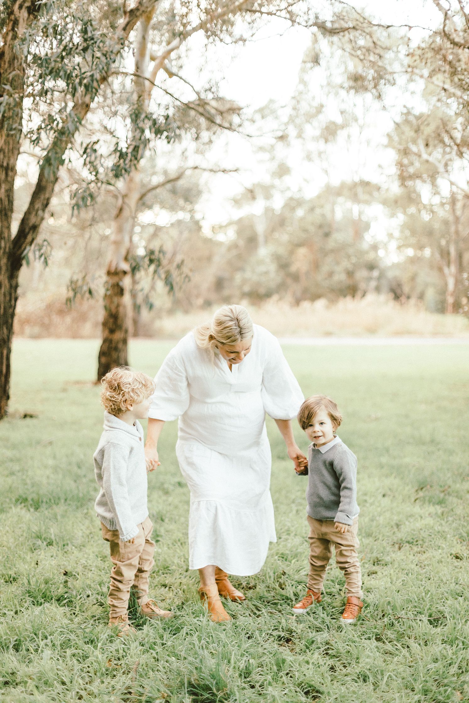 Family walking together through grassy field during sunset maternity photo session.